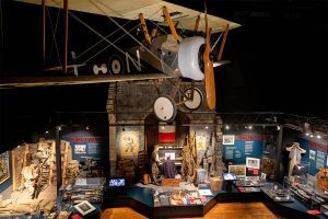 Top view of a World War I biplane over museum displays of WWI.