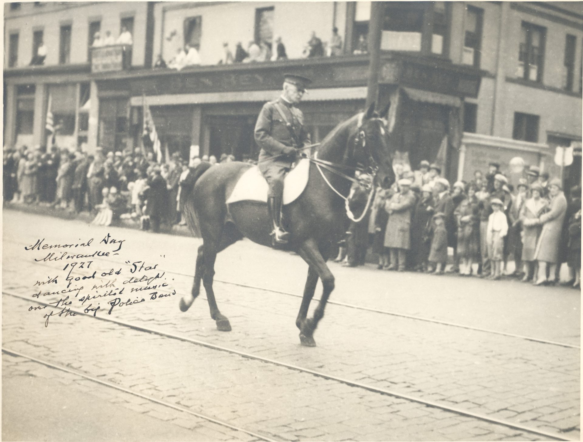 uniformed man riding a horse in a parade in the early 20th century