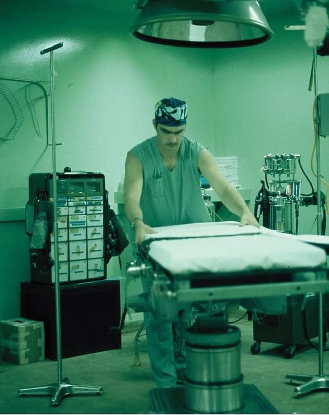 Man in surgical scrubs standing over a table in an operating room