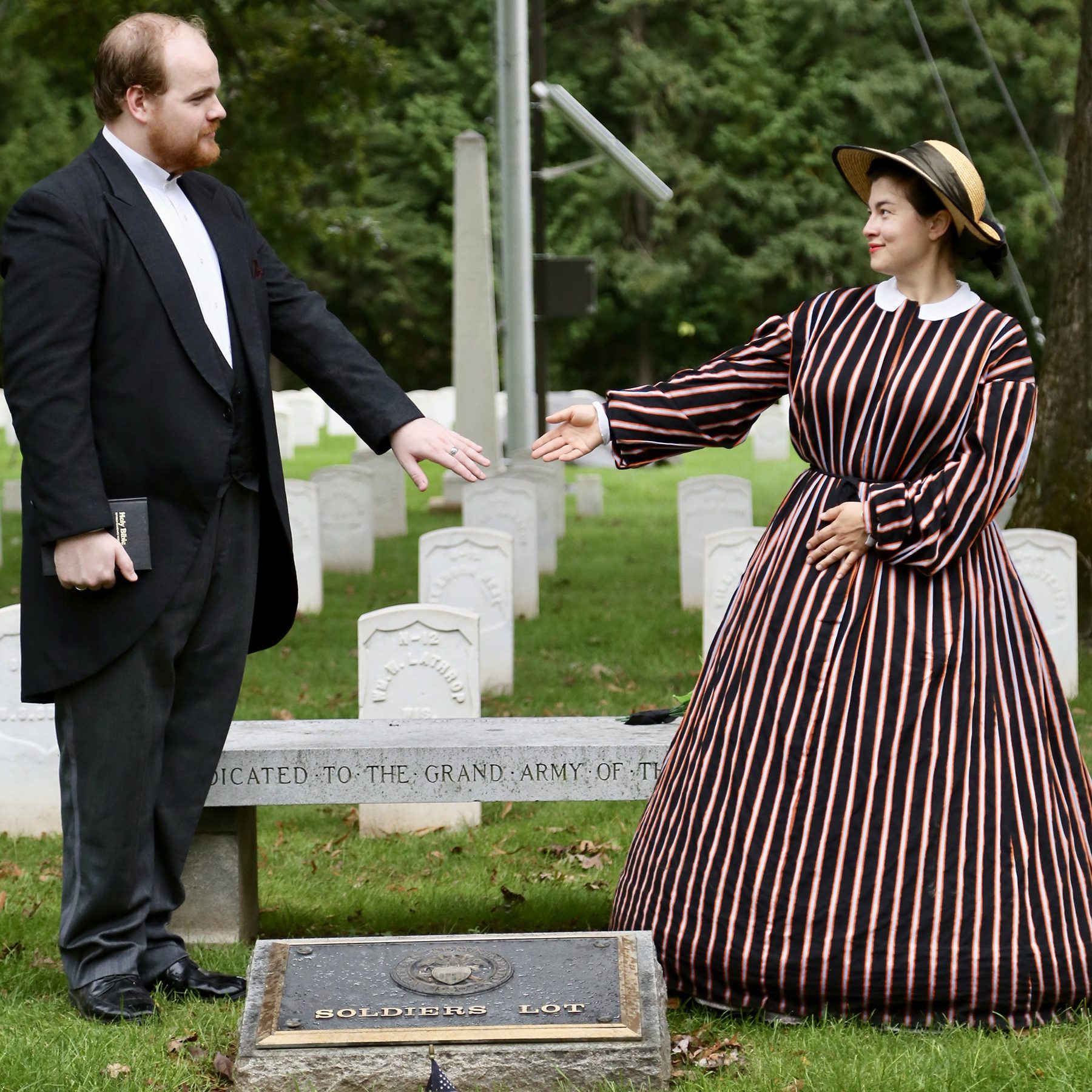 Man and woman dressed in 19th century costumes talking in a cemetery