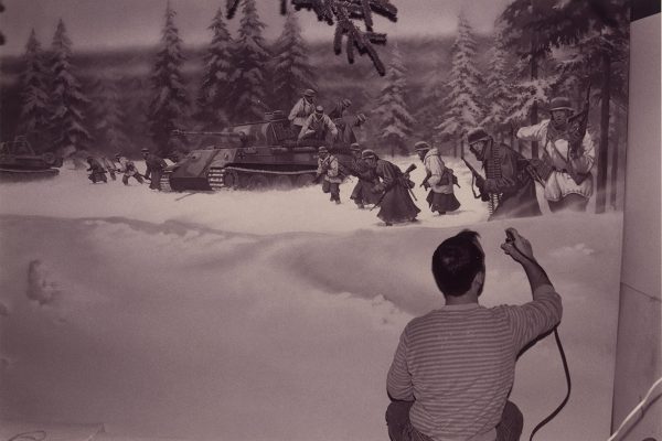 Man painting a mural of a snowy forest with soldiers.