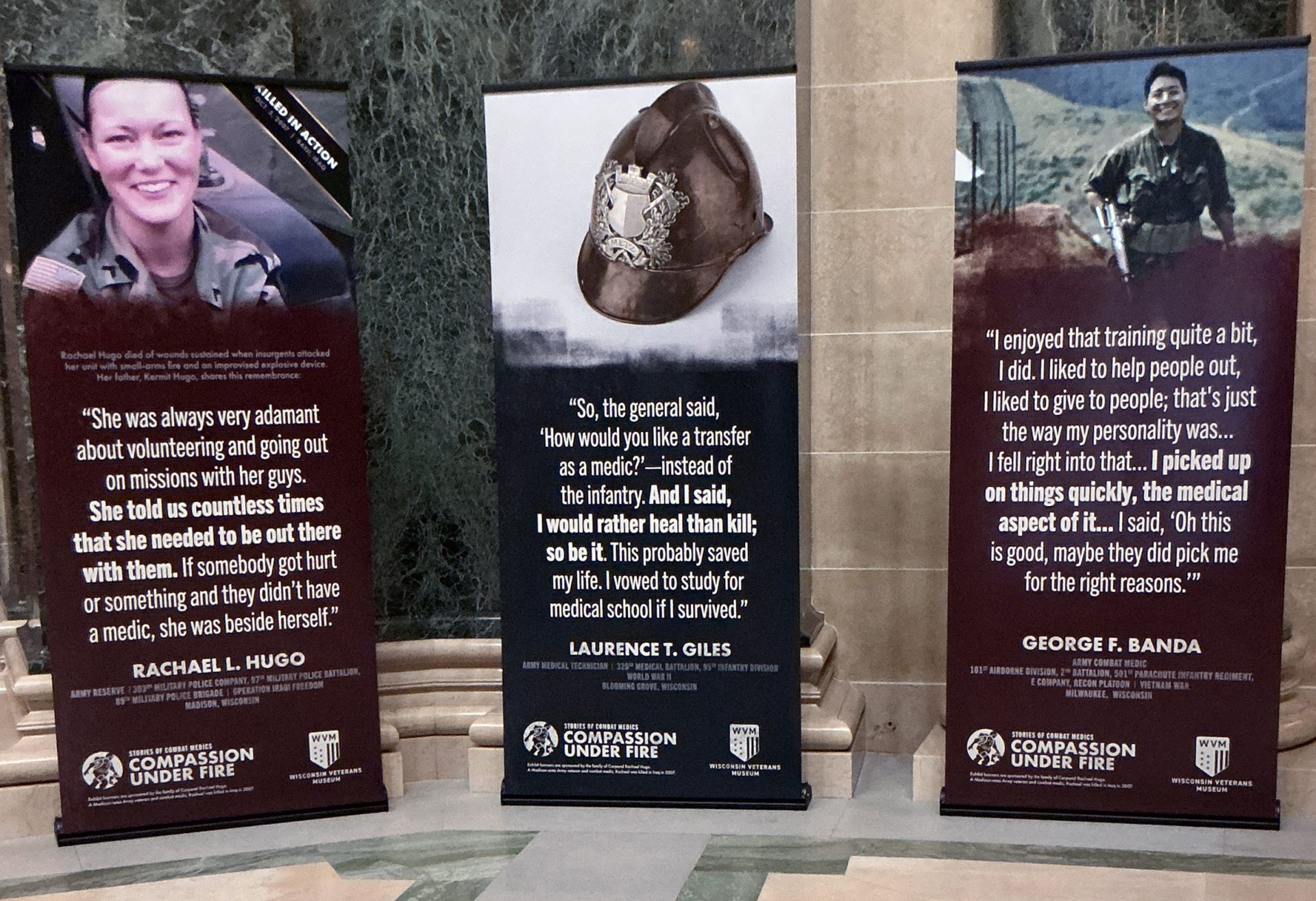 Image of three banners with images and text in a hall."
