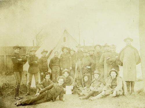 Group of soldiers in campaign hats, sack coats with or without chevrons on the sleeves, uniform trousers, and boots.